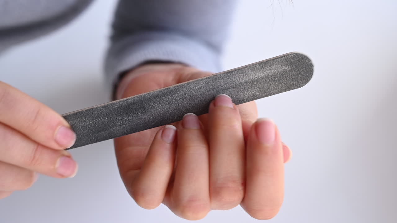 Close up of hands filing nails with a grey nail file during a self care routine