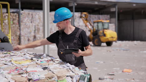 laborer at recycling center checks if recycled paper bales are bound firmly