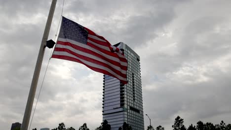 american flag flying in the wind with a building in the background in houston, texas with stable video