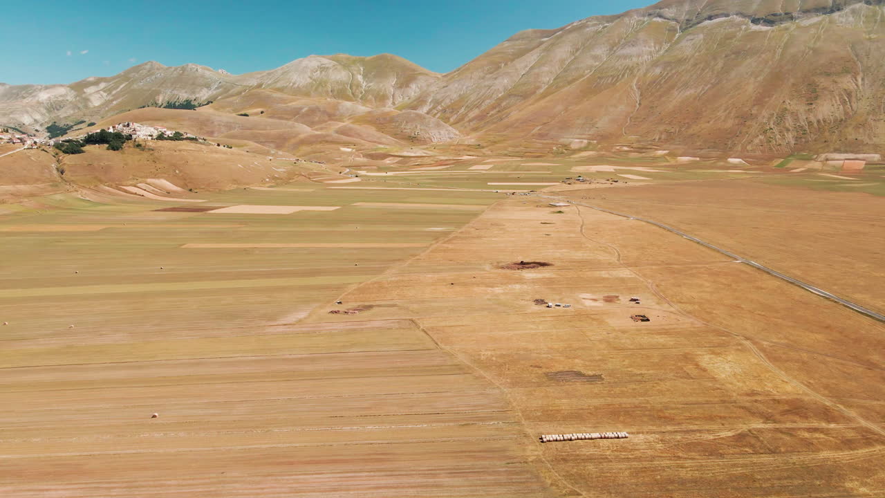vista aérea de piana grande con campos de campo y pueblo de castelluccio en la distancia en toscana, italia