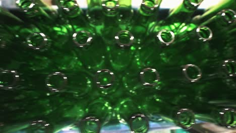 Top-down-view-of-glass-beer-bottles-being-transported-through-automated-production-line-in-a-factory