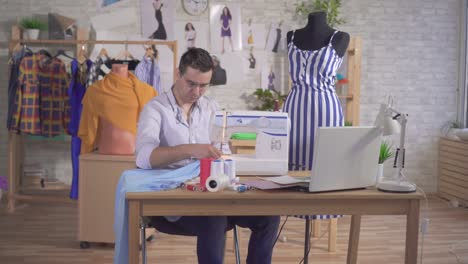hombre diseñador de moda sastre coser en una máquina de coser en el estudio