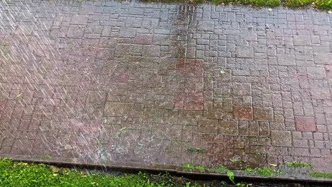 rain splashes onto wet sidewalk creating rhythmic patterns and bouncing droplets in still frame
