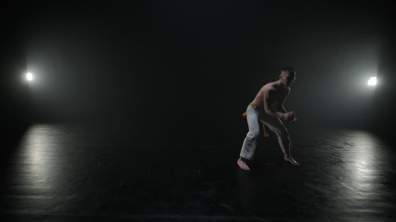 Lottatori di Capoeira che eseguono mosse dinamiche sul palco. Arti marziali, danza e acrobazie in azione. Atleti a torso nudo che mostrano forza, flessibilità e tecnica sotto i riflettori