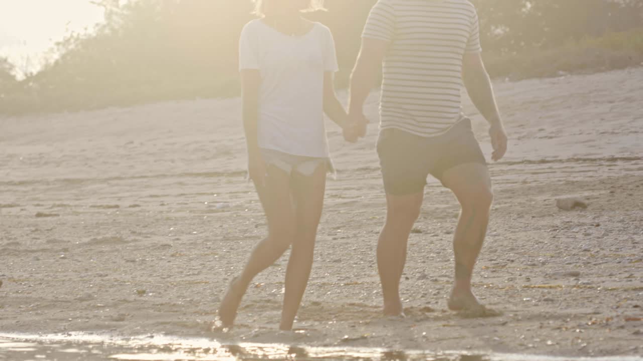 남녀가 손을 잡고 해가 지는 해변을 고 있다