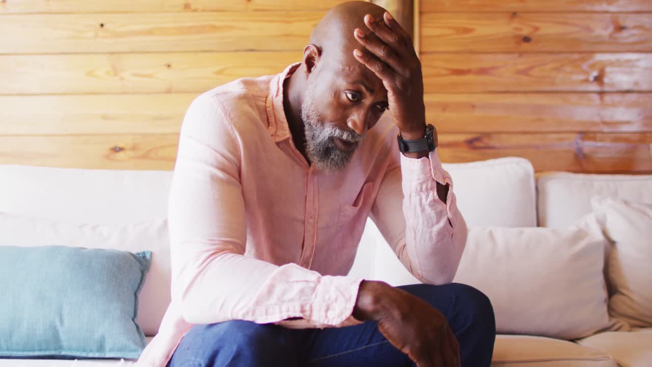 Senior african american man spending time in log cabin and sitting on couch, slow motion