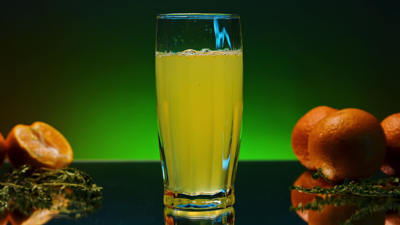 jugo de naranja en un vaso con naranjas y hierbas