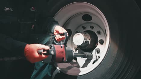 mecánico que utiliza una llave de impacto para apretar las tuercas de un neumático grande de un remolque
