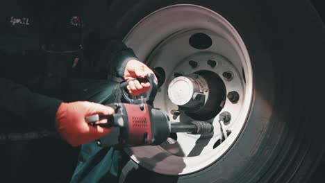 mechanic using impact wrench to tight down lug nuts of a big tire from a trailer