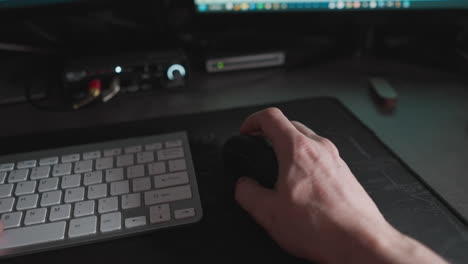 pov shot of hands typing and using a mouse in dim light, with occasional glances at a phone for time-checks during a focused work session