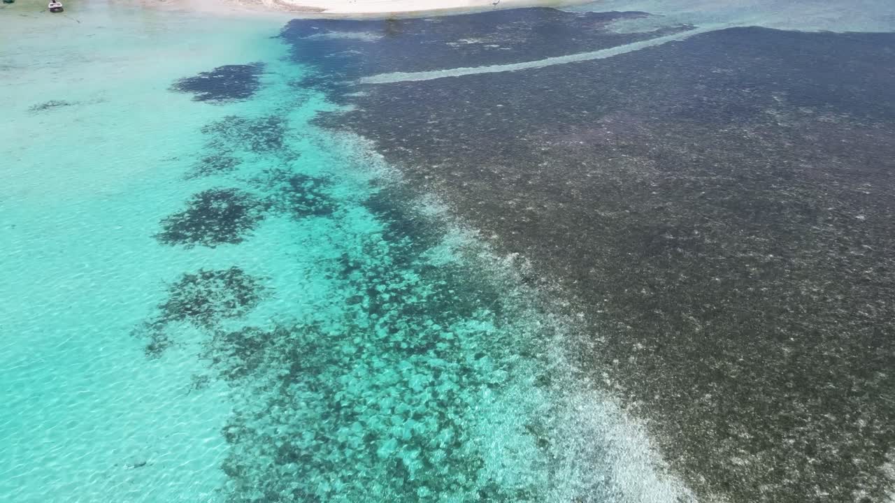Aerial view of shallow turquoise waters with visible coral formations in the Maldives.