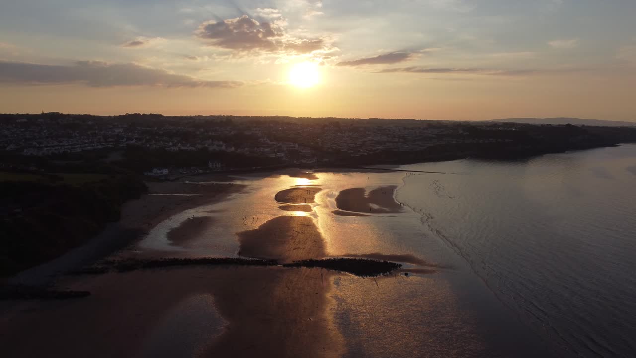 Raggi dorati celestiali del tramonto, vista aerea riflessa su una romantica costa di spiaggia esotica, carrellata alta a destra