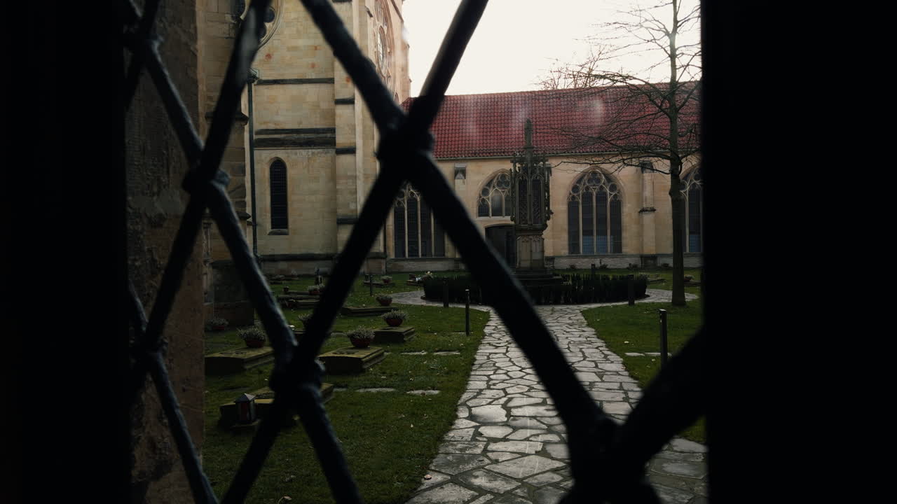 Historisk kirkeplads med gotisk arkitektur, stensti og gamle grave omgivet af klostermure, der viser middelalderlig religiøs arv og en fredfyldt historisk atmosfære