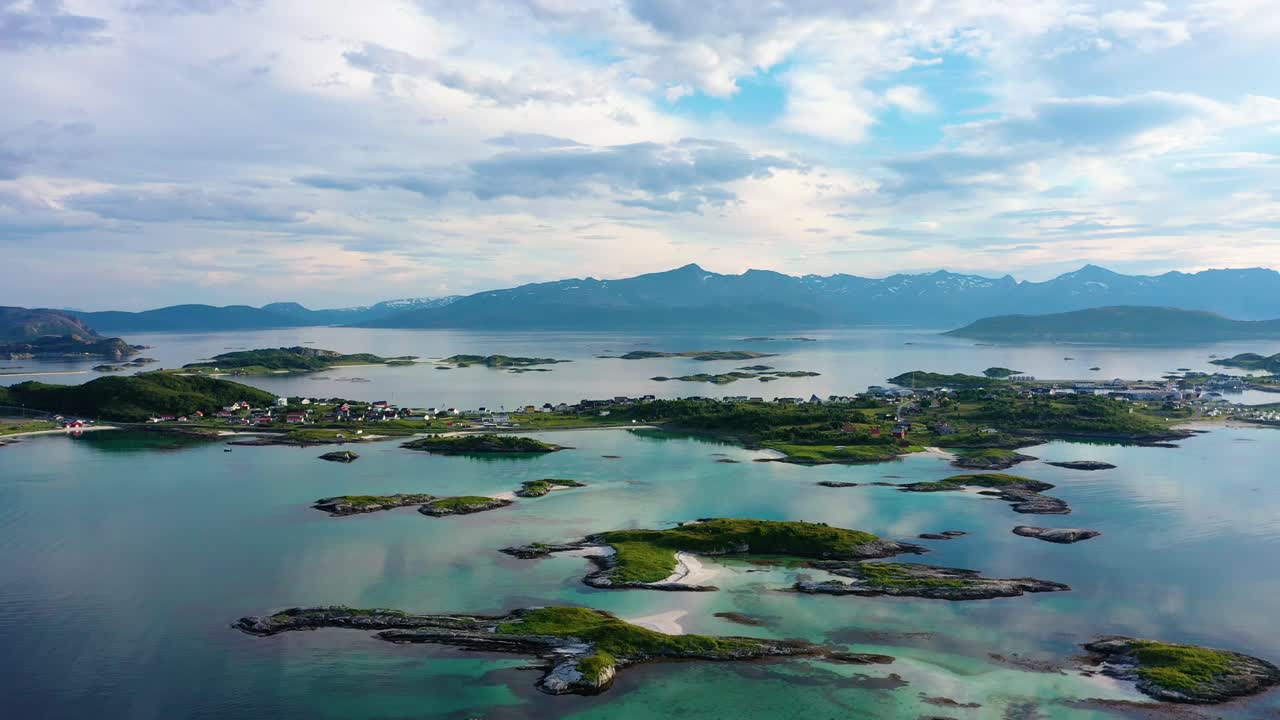 Aerial view overlooking turquoise water and the Sommaroy islands, at the Arctic ocean, partly sunny, summer day, in Troms, Nordland, Norway - tilt down, drone shot