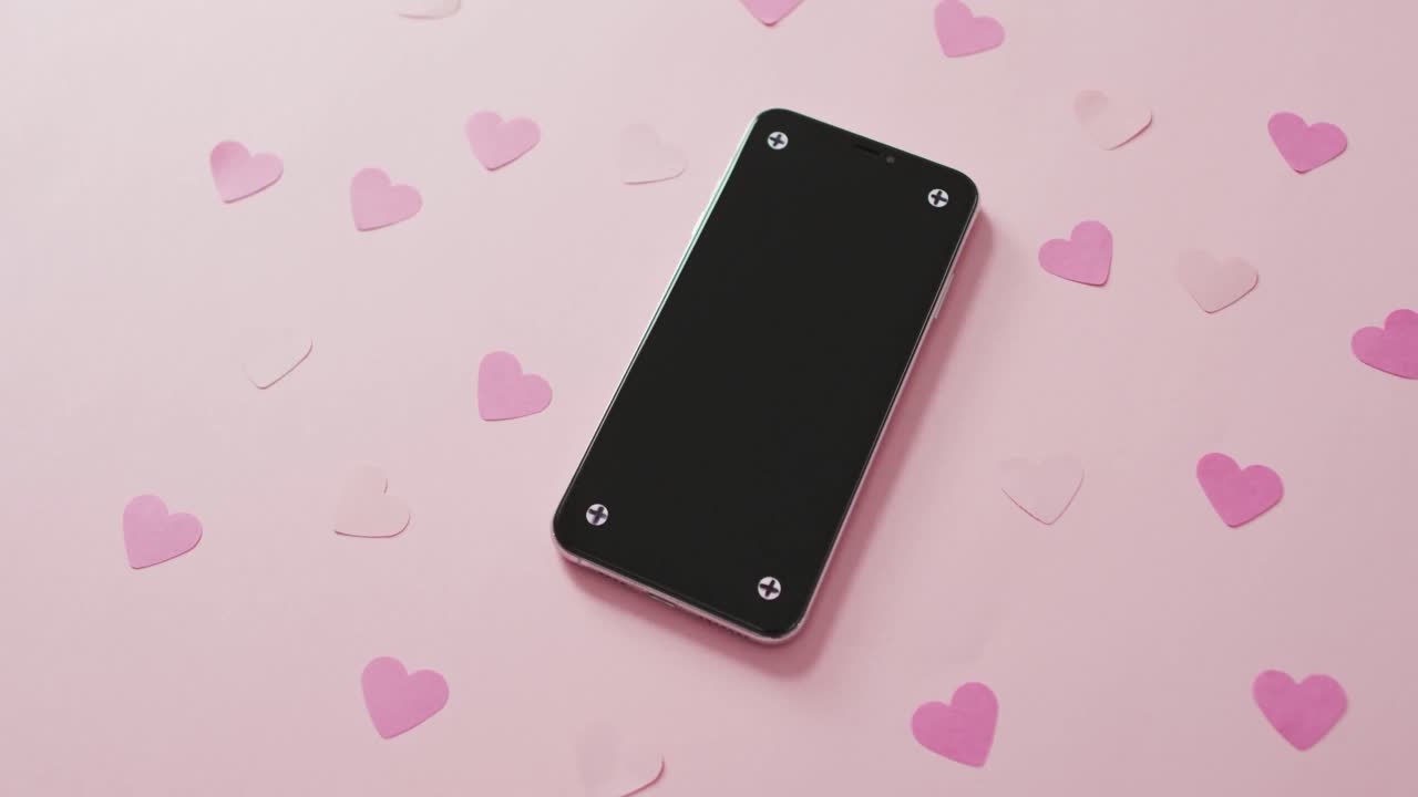 Smartphone and paper hearts on white background at valentine's day