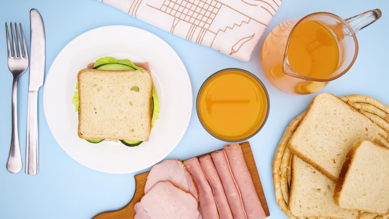 朝食用の手作りサンドイッチが、他の食べ物や飲み物と一緒にテーブルの上を円を描くように動く - ストップモーション