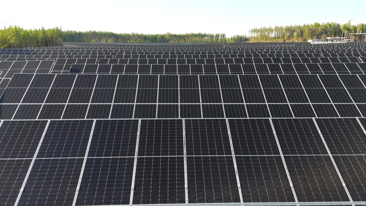 Ripresa aerea a bassa quota di un parco solare che evidenzia file di pannelli solari bifacciali che si estendono fino all'orizzonte.