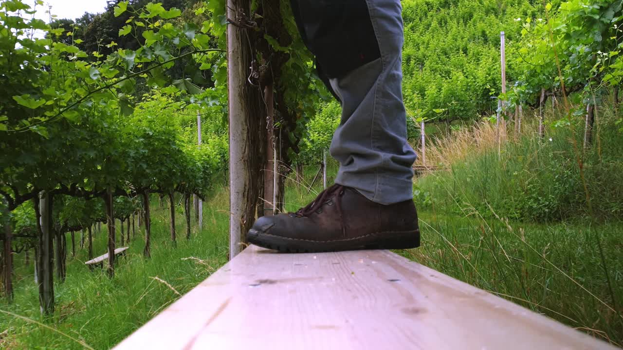 Closeup of a workers feet stepping off a bench.