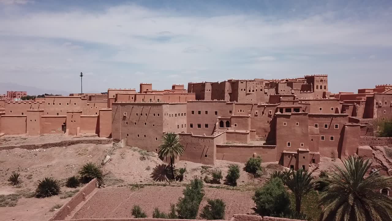 Ripresa cinematografica con drone di un tradizionale villaggio berbero fortificato costruito in terra e argilla nella regione desertica di Ouarzazate.