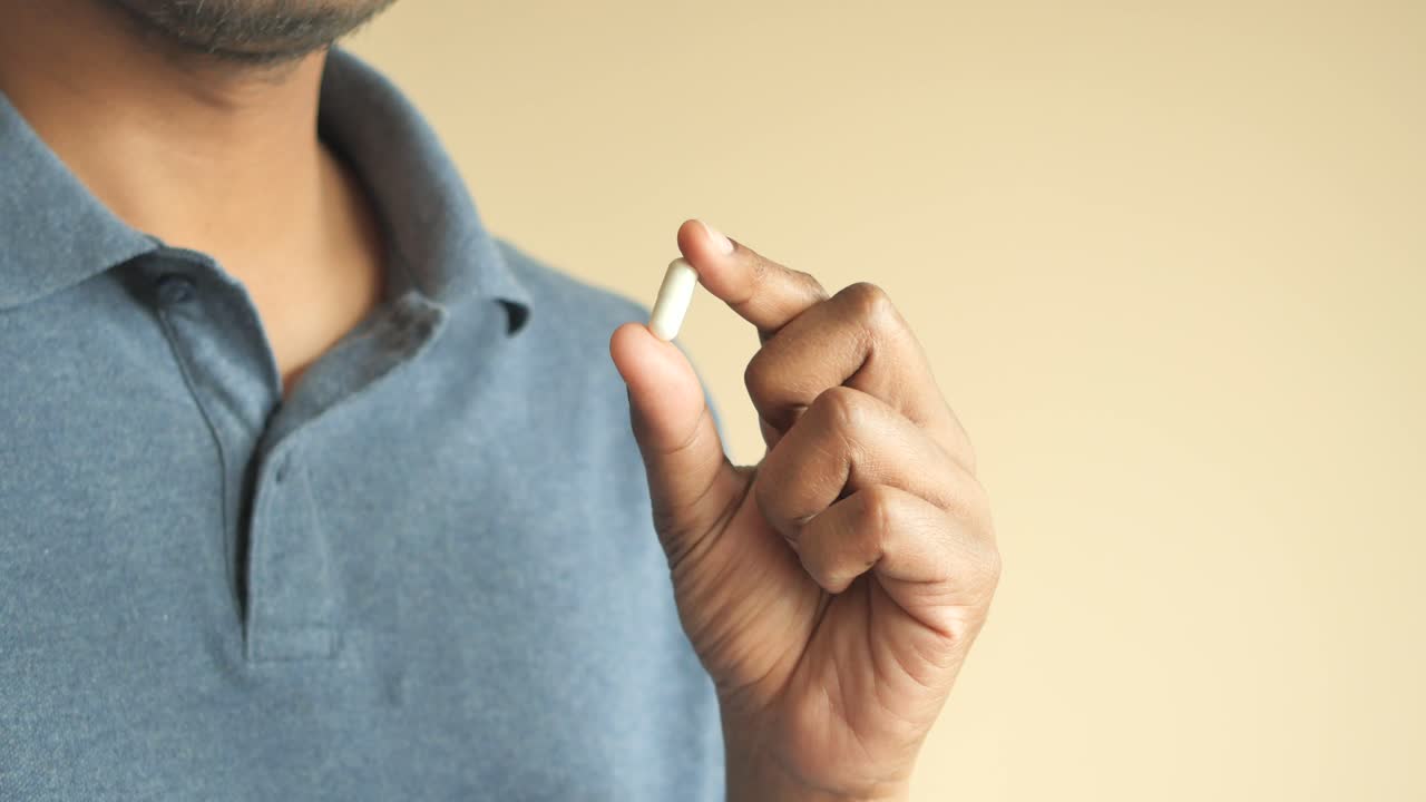 persona que sostiene una cápsula blanca