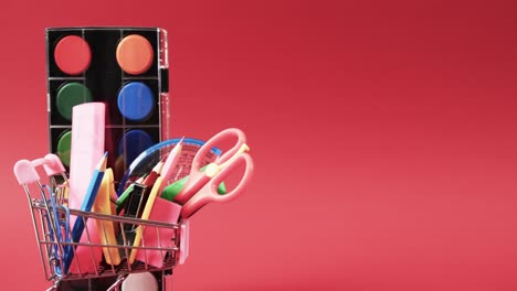 cerrar el carrito de compras en miniatura materiales escolares y espacio de copia en fondo rojo