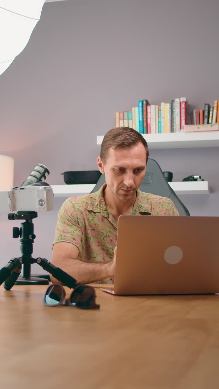Man working from home office with camera and laptop