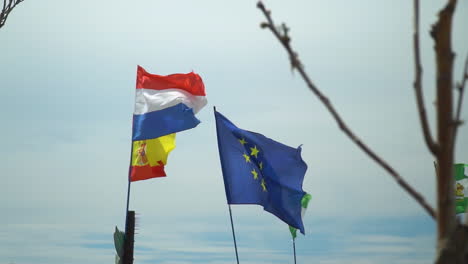 flag of eu, france, spain and andalucia waving in slow motion in front of pale blue sky