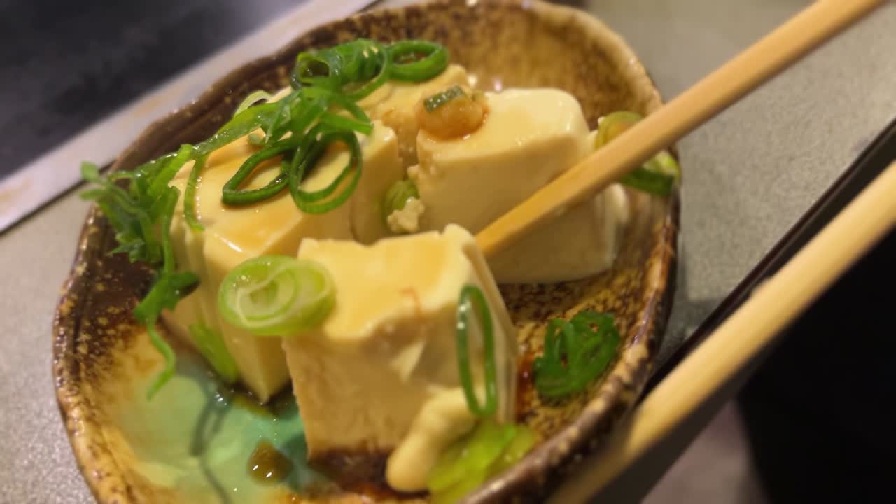Comiendo tofu frío japonés con palillos