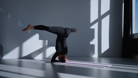 vrouw doet een yoga headstand pose in een studio