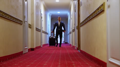 businessman in hotel. full-length portrait of a man with suitcase. handsome man in elegant suit moving along the corridor of a hotel to the room.
