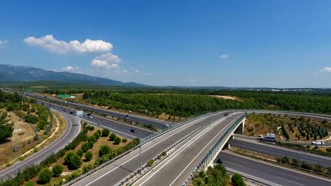 aerial shot over a busy highway intersection which winds it way through lush green fields and