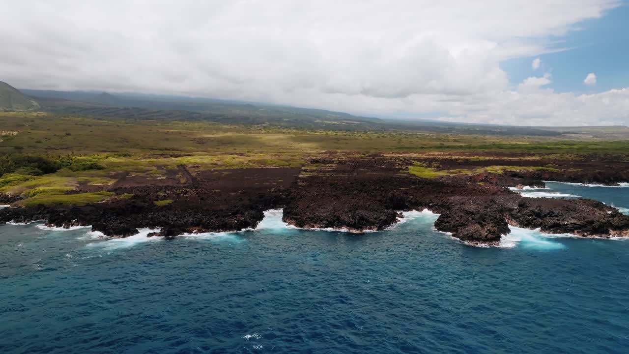 하와이의 큰 섬에 있는 어두운 용암 바위에 부딪히는 파도가 있는 목가적인 바다