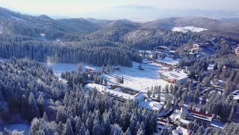 Flying-upward-and-forward-above-a-snowy-forest-in-Brasov,-Romania