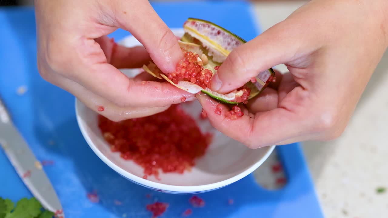 Hands extracting finger lime pulp over a bowl in a bright kitchen. Close-up view highlights the vibrant colors and textures