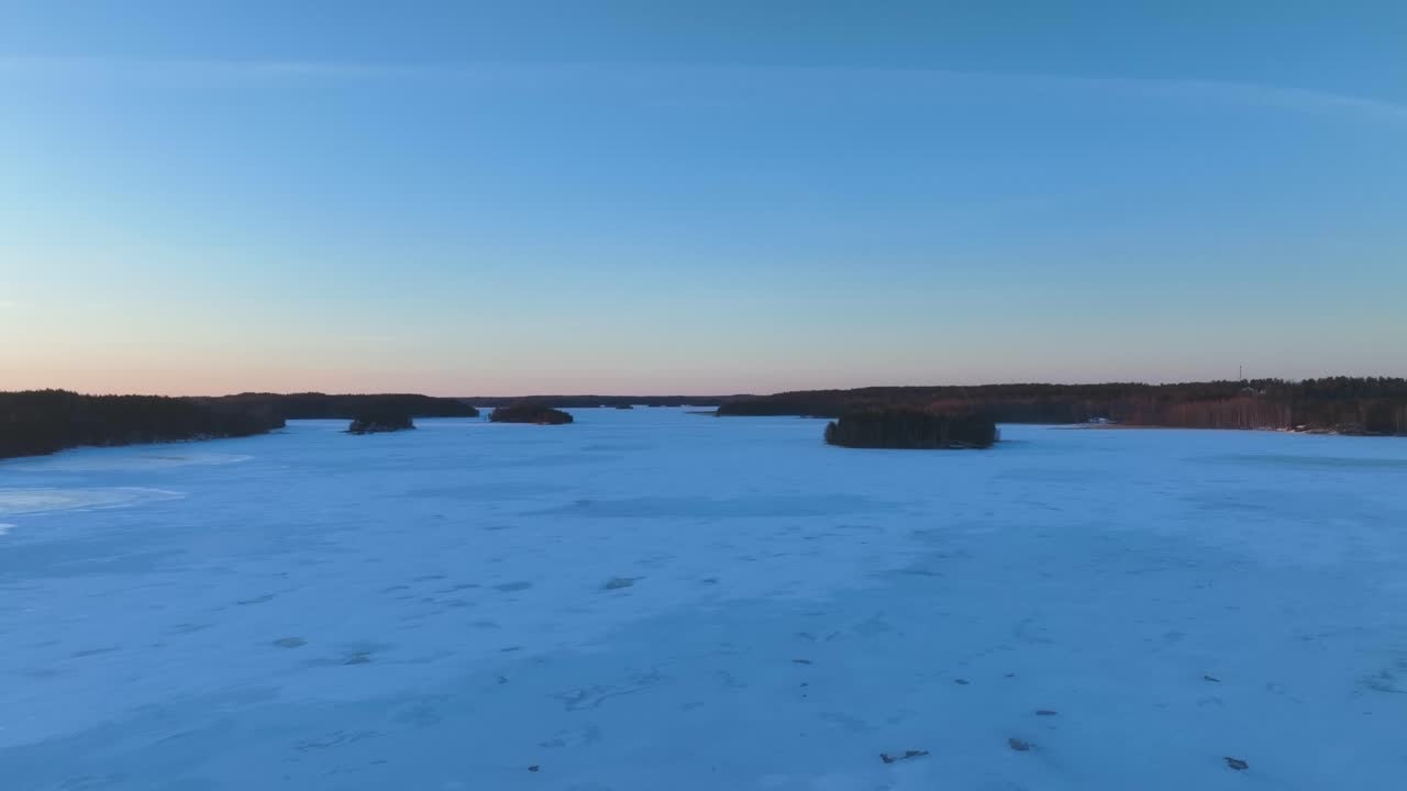 Drone flight over a frozen lake in Finland revealing the sunset