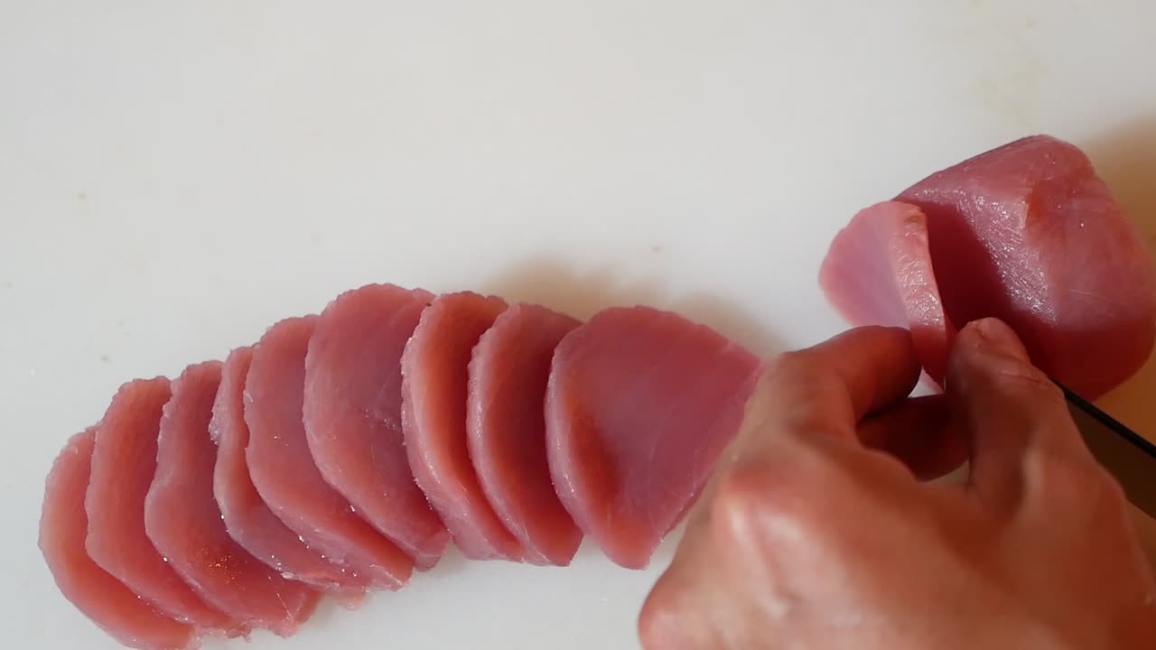 El, pembe Maguro'yu küçük lokma sashimiler halinde dilimlemek için bıçak kullanıyor, Yakın Çekim.