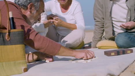 Elderly-men-and-women-playing-dominoes-on-beach-on-summer-day