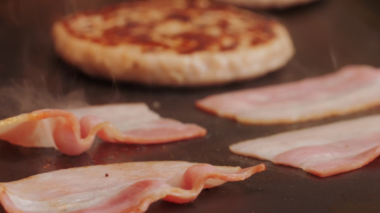 Cooking American fat smash burger and bacon slice on grill close-up. Chiken or fish cutlet smashing by burger press. The chef in kitchen of the restaurant making cutlets for burgers - smash burger beefsteak. Fast and street food concept. High quality 4k footage