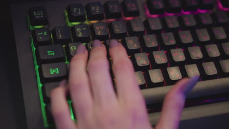 close up hand view of lady in fluffy sweater typing on rgb mechanical keyboard with glowing backlit keys and polished nails in cozy tech setup under ambient colorful lighting
