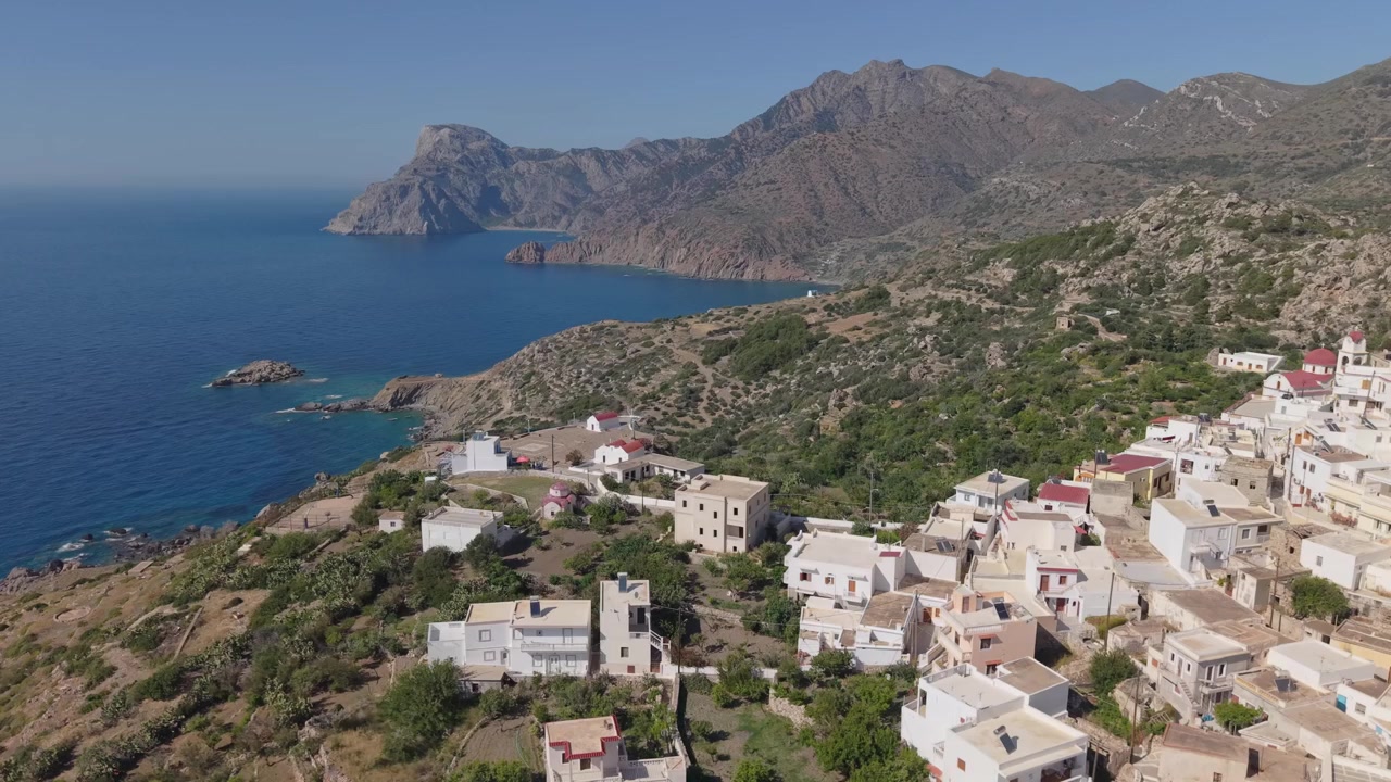 Karpathos'un dramatik manzarası ve Ege Denizi'nin panoramik manzaralarıyla çevrili, dağ yamacına tünemiş Mesochori Köyü'nü gösteren havadan geri çekilme çekimi.