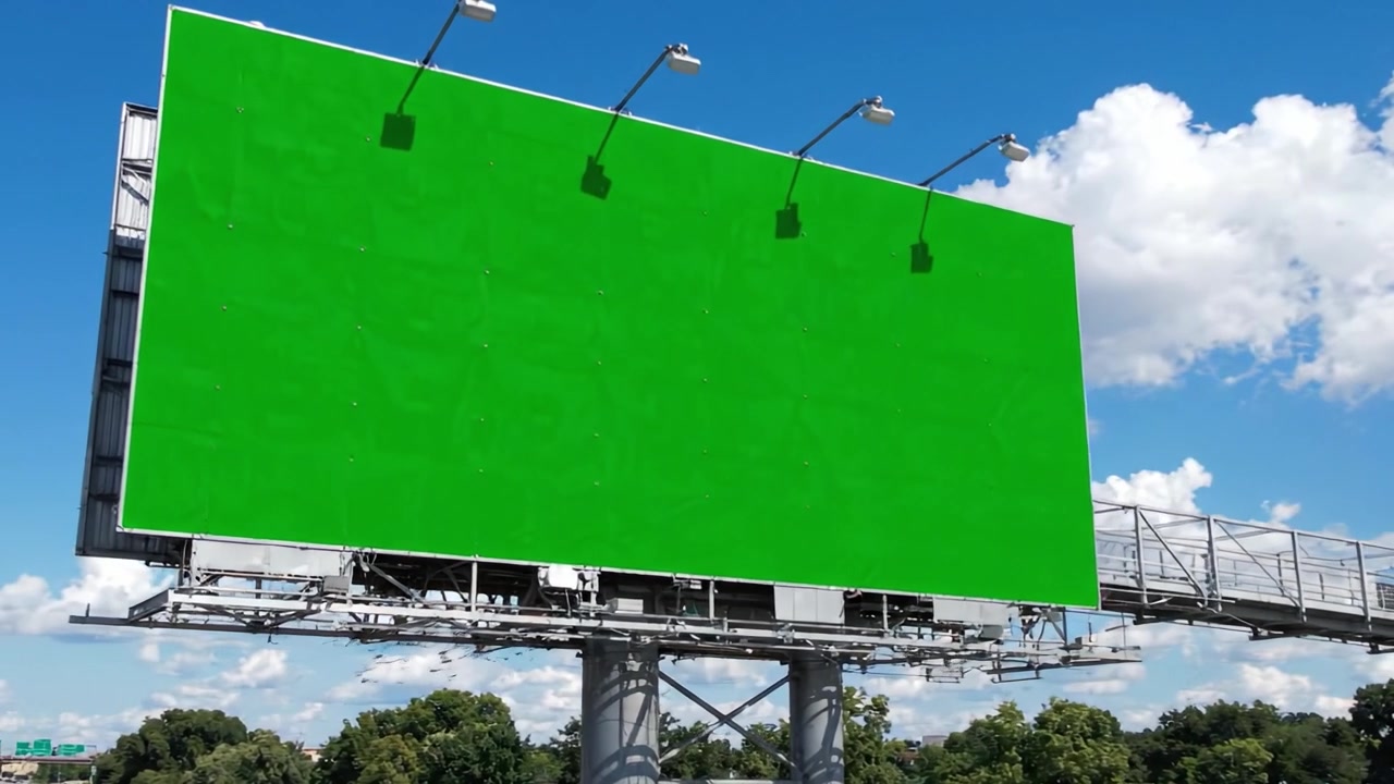 En levende grøn billboard med klar himmel og skyer fanget i to rammer, der viser et blankt lærred for reklame muligheder.