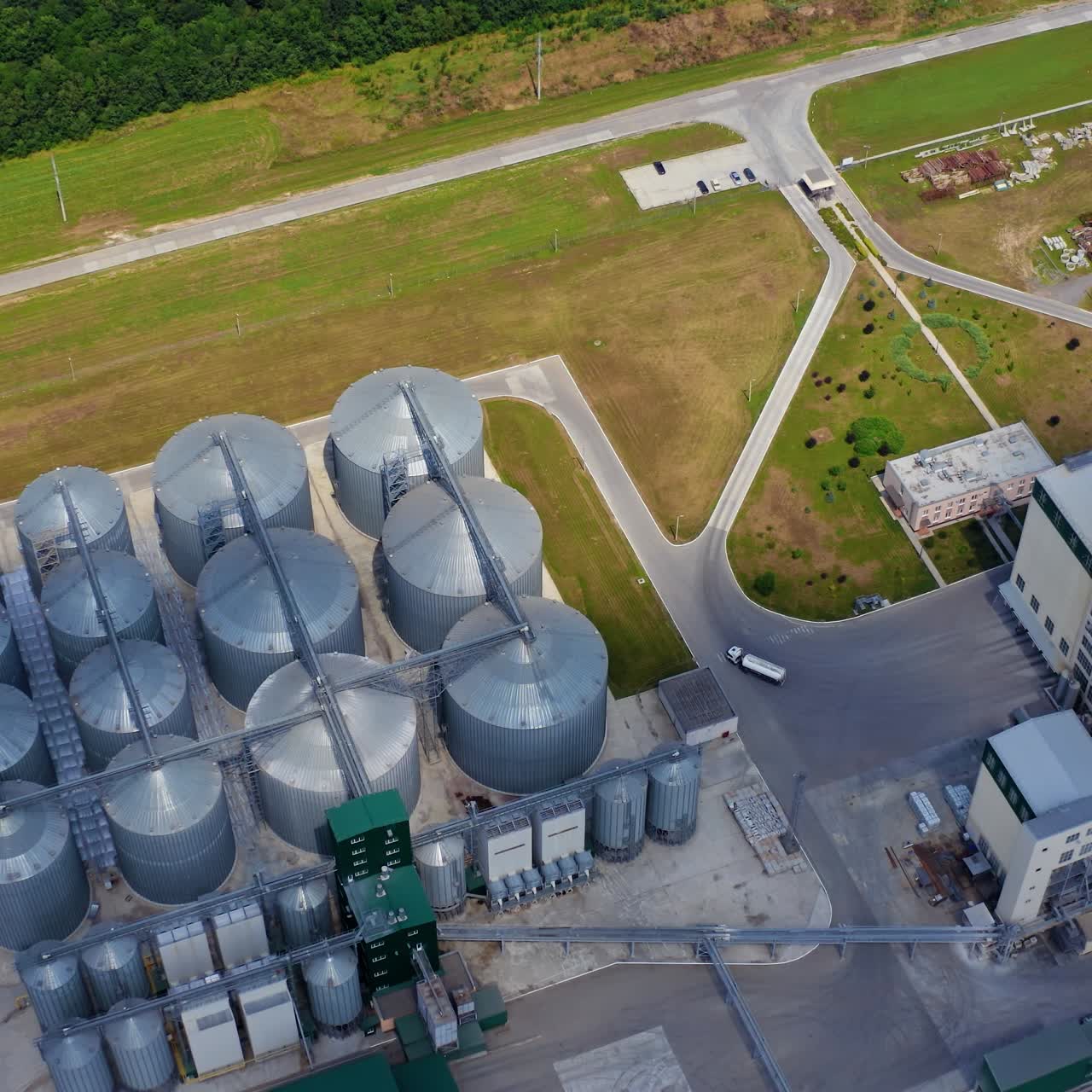 Farmland with grain granary. Flight over huge agricultural zone with steel elevators. Silos for harvest on modern factory in the field. Aerial view