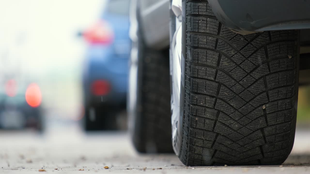 primer plano de un coche estacionado en un lado de la calle de la ciudad con neumáticos de goma de invierno nuevos.