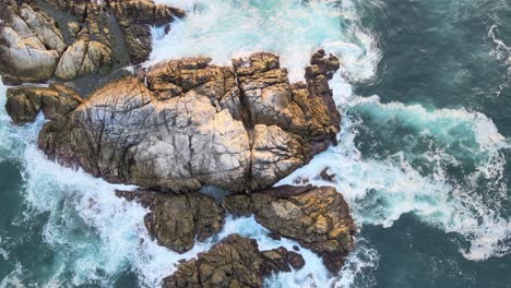 Zenith-view-above-rocky-shore,-with-waves-at-sunrise