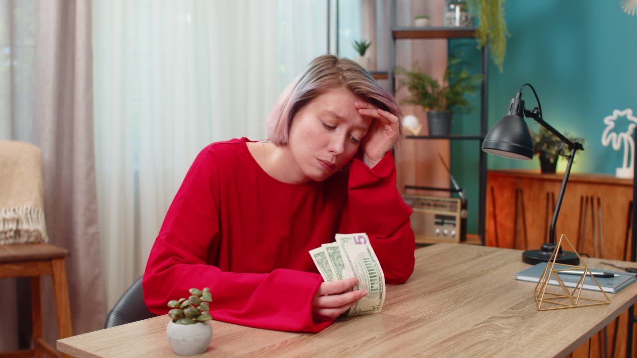 Young woman unhappily counts money frowning stressed demonstrating financial problems lack of funds