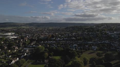 aerial view of portishead parish near bristol, drone moving forward above the houses and the green gardens, blue and cloudy sky in the background