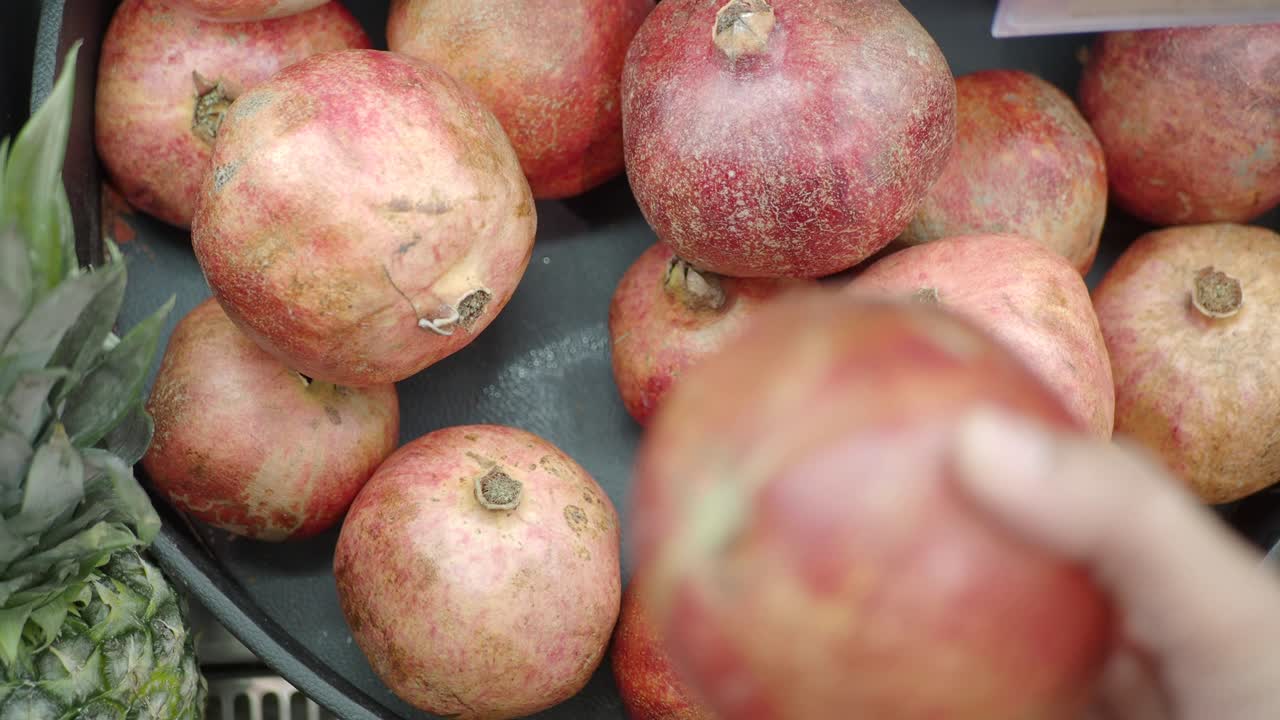 Hånd plukker friske granatæbler fra en markedsudstilling