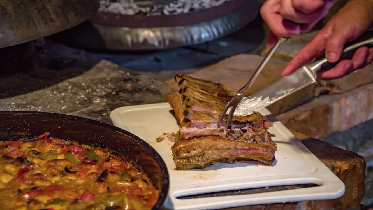 나무 화덕 옆에 돼지 갈비 조각을 자르는 사람의 클로즈업 샷