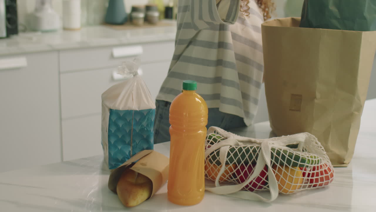Smiling Girl Taking Off Groceries from Bags in Kitchen