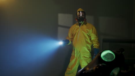 hazmat suit wearing man explores a dark room